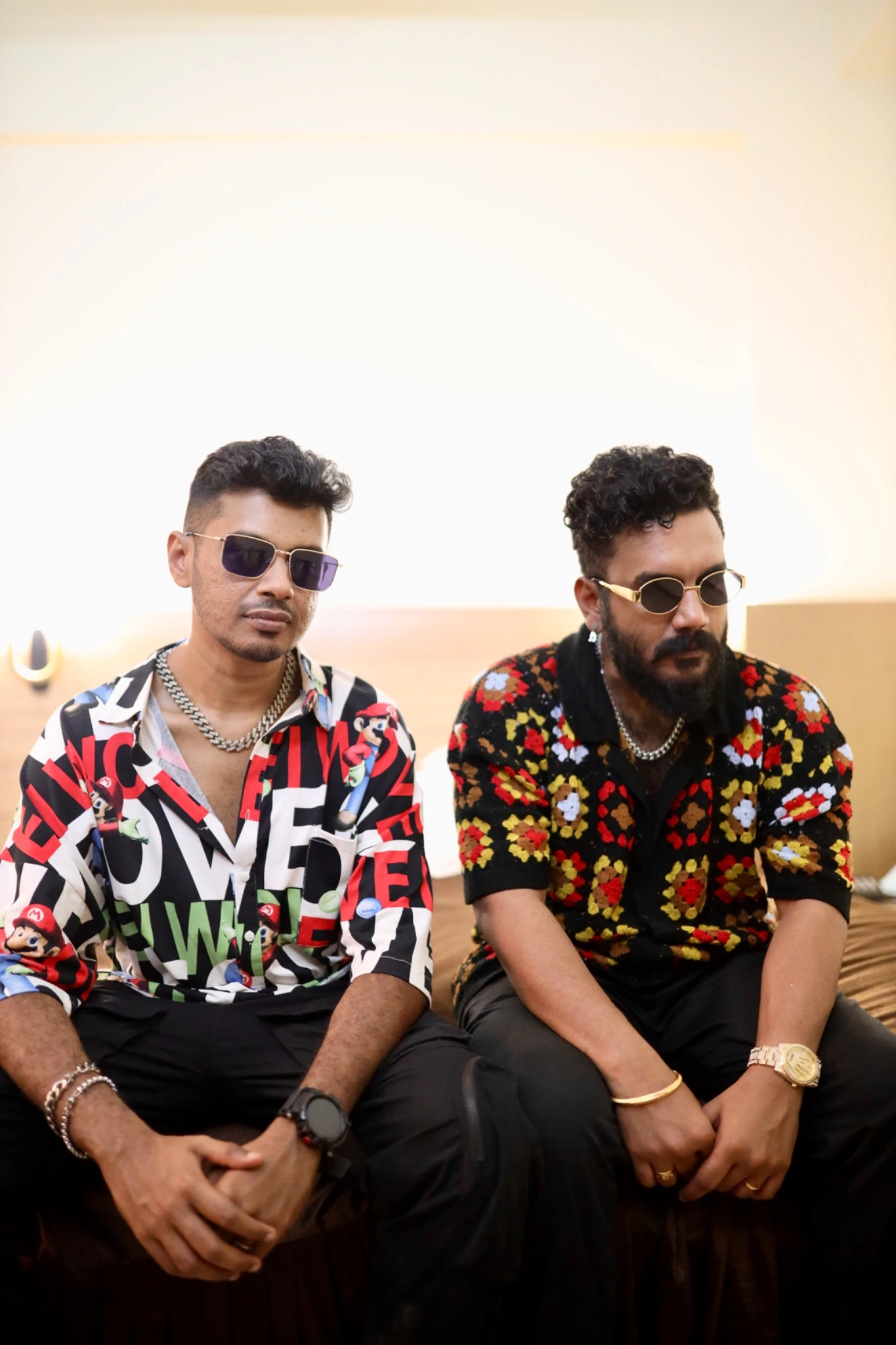 Fejo and Adarsh seated together, wearing patterned shirts and sunglasses