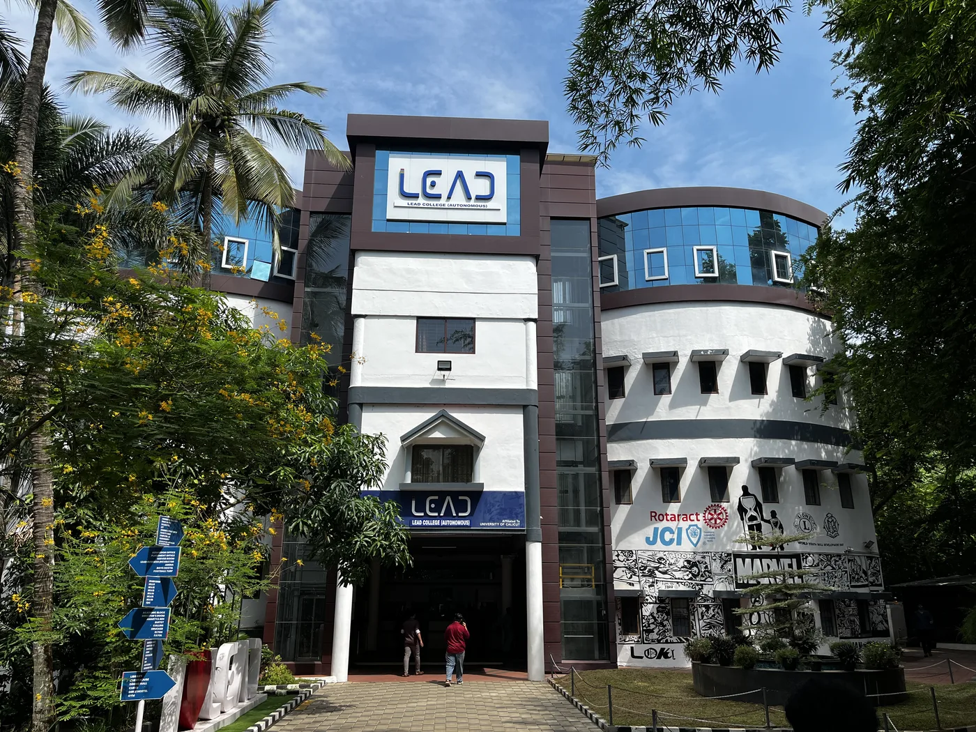 LEAD College Autonomous building entrance, framed by coconut palms and trees
